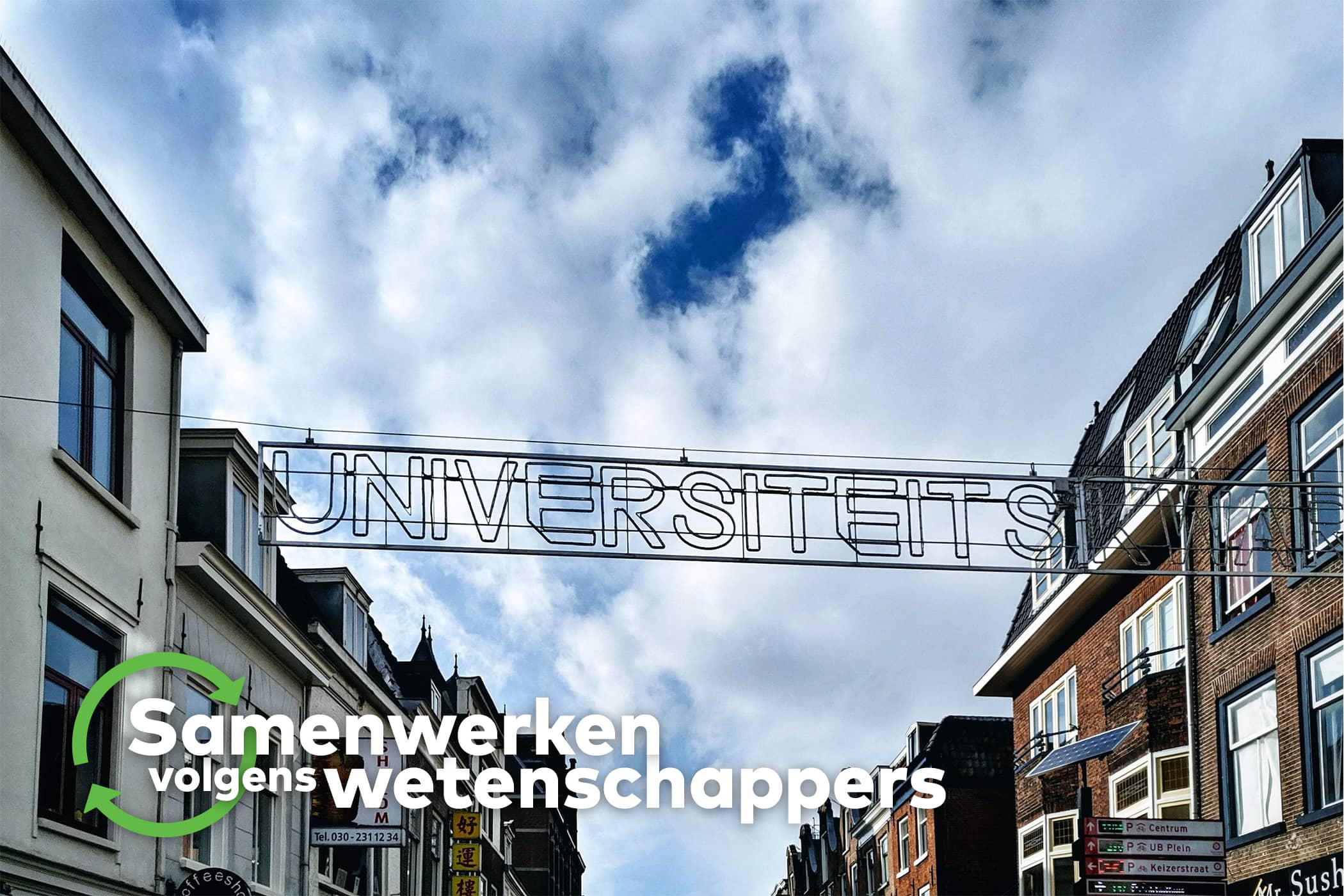 Een bord boven een straat waarop 'universiteitskwartier'staat. Erachter staan gebouwen.