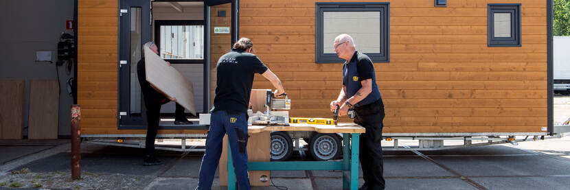Drie personen werken aan een tiny house