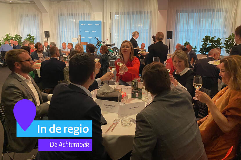 Een aantal deelnemers zitten met elkaar aan tafel. Zij proosten.