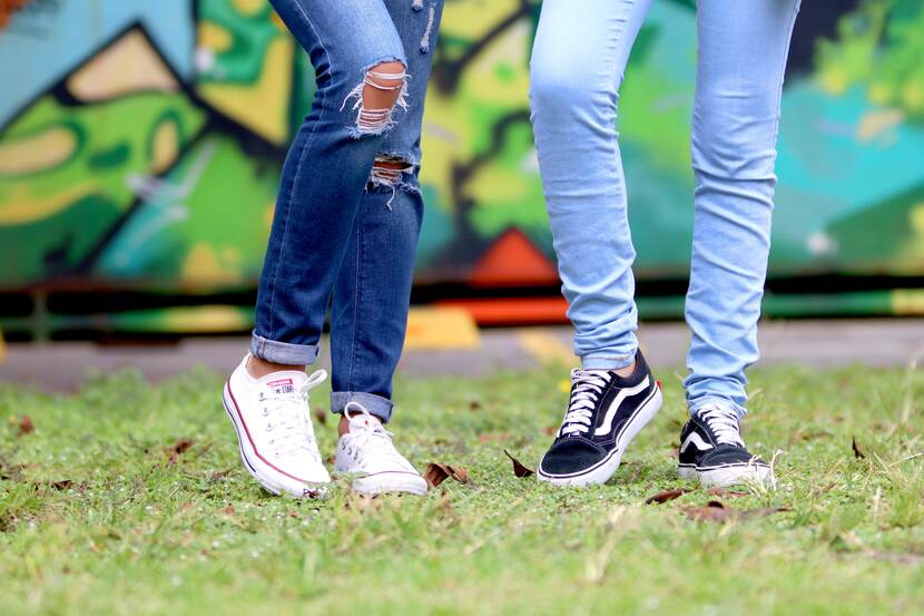 Twee paar benen in jeans en sneakers