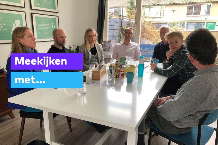 Een groep mensen zit met Lot van Hooijdonk aan tafel