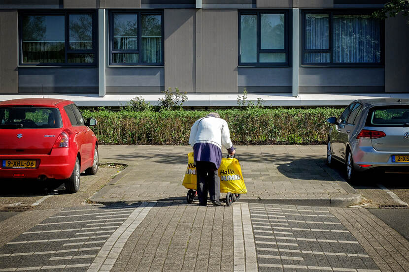 Oude vrouw met rollator en boodschappentassen