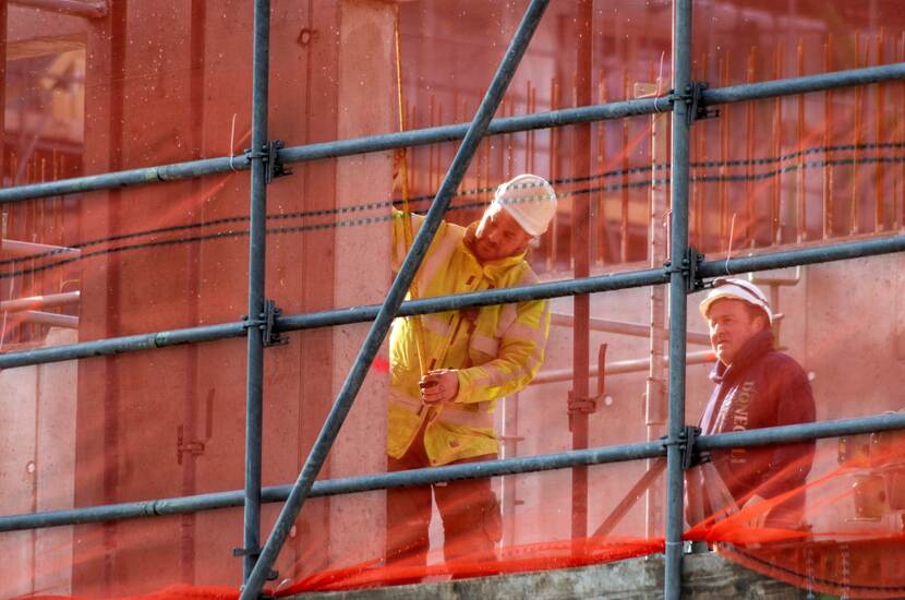 Twee bouwvakkers werken op een steiger