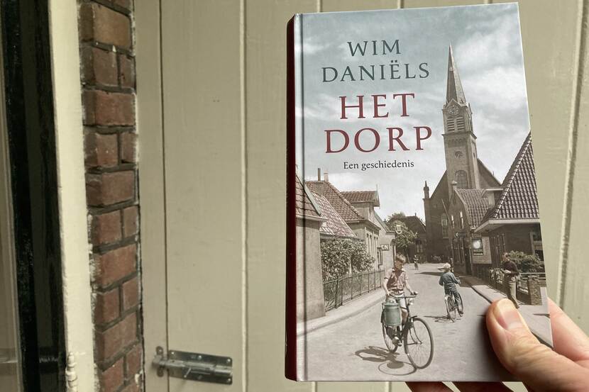 Iemand houdt het boek Het dorp van Wim Daniëls vast