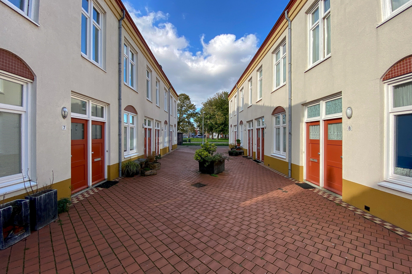 foto van een straat met gele huizen met rode deuren