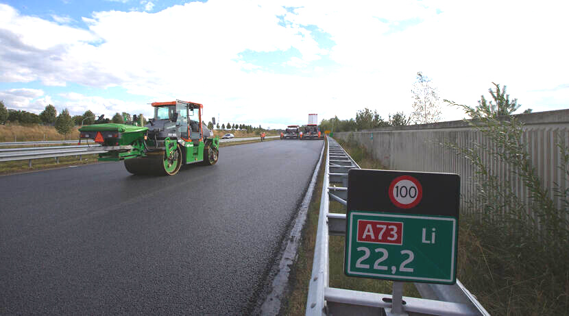 Een foto van de A73 waar het asfalt opnieuw wordt aangelegd met een duurzamere methode