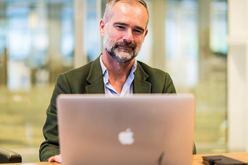 Ron de Koning glimlacht vanachter zijn laptop