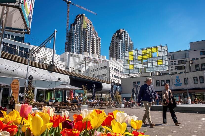 Mensen lopen voorbij met de skyline van Den Haag op de achtergrond.