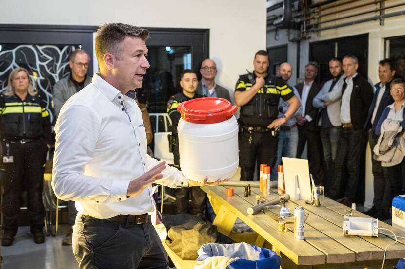 Man legt iets uit aan politiemensen en anderen die om hem heen staan