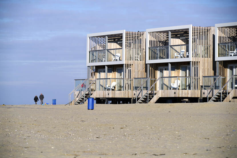 Foto van de kust met twee wandelende mensen in de verte