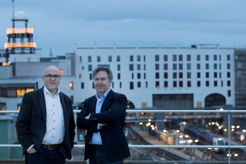 Peter Bertholet en Charles Claessens op het dak van het vroegere CBS-gebouw in Heerlen met op de achtergrond het nieuwe station.