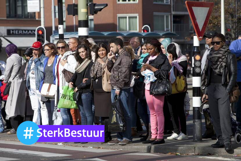 Een groep voetgangers staat bij het stoplicht