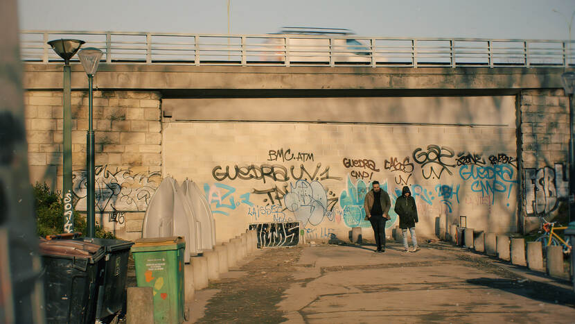 Twee mensen lopen voor muur met graffiti