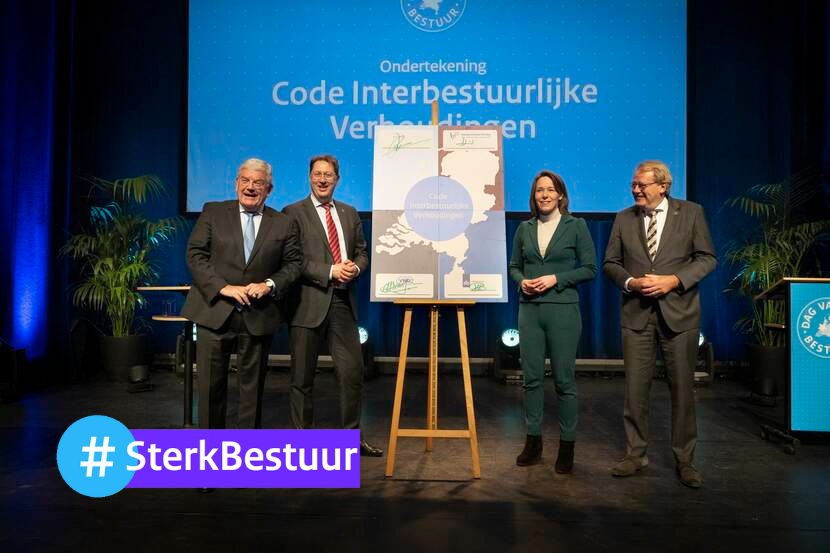 Vier mensen poseren rondom de schildersezel met Code Interbestuurlijke Verhoudingen