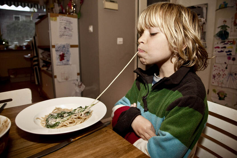 Een kind eet een spaghettisliert