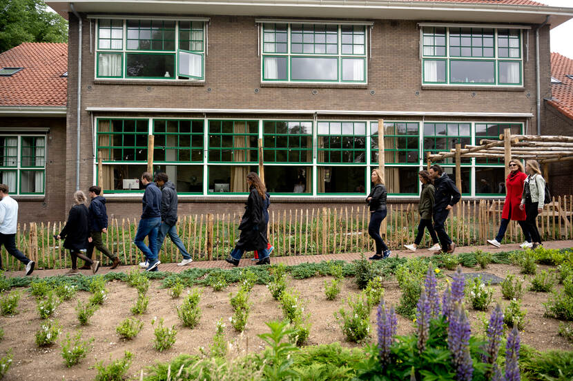 Mensen lopen langs een gebouw en een tuin