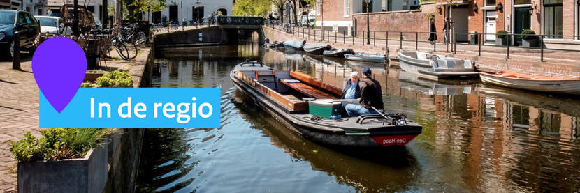 Sloep met 2 mannen erin. Links staat de tekst In de regio