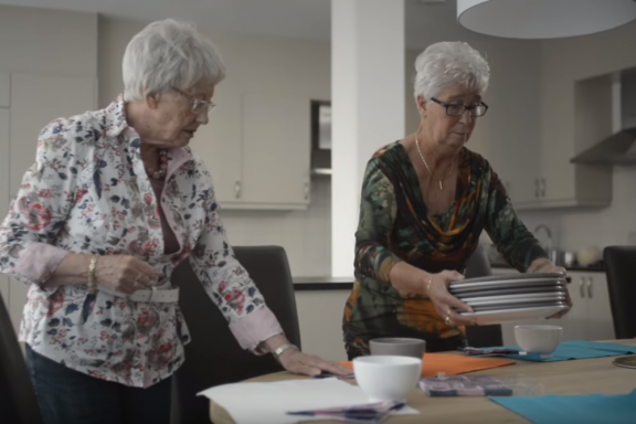Twee oudere vrouwen dekken een tafel