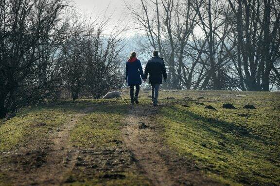 Mensen lopen hand in hand tussen bomen